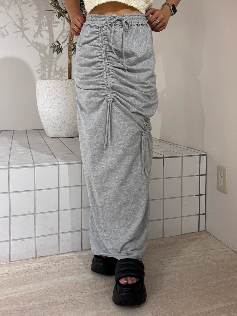 ホワイト系のニット/セーター、グレー系のスカート、ブラック系のサンダルを着用したレディースの夏コーディネートの5枚目の写真