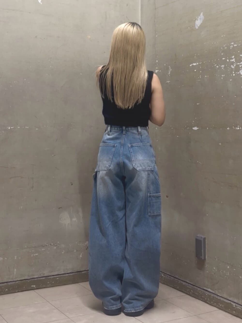ブルー系のデニムパンツ、ブラック系のニット/セーター、ブラック系のサンダルを着用したレディースの夏コーディネートの3枚目の写真