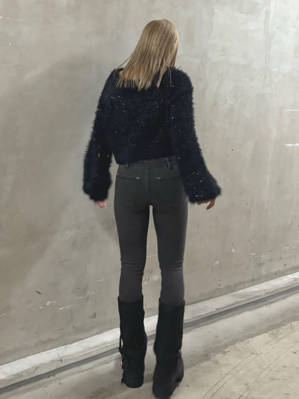 ブラック系のブーツ、ブラック系のニット/セーター、グレー系のデニムパンツを着用したレディースの冬コーディネートの3枚目の写真