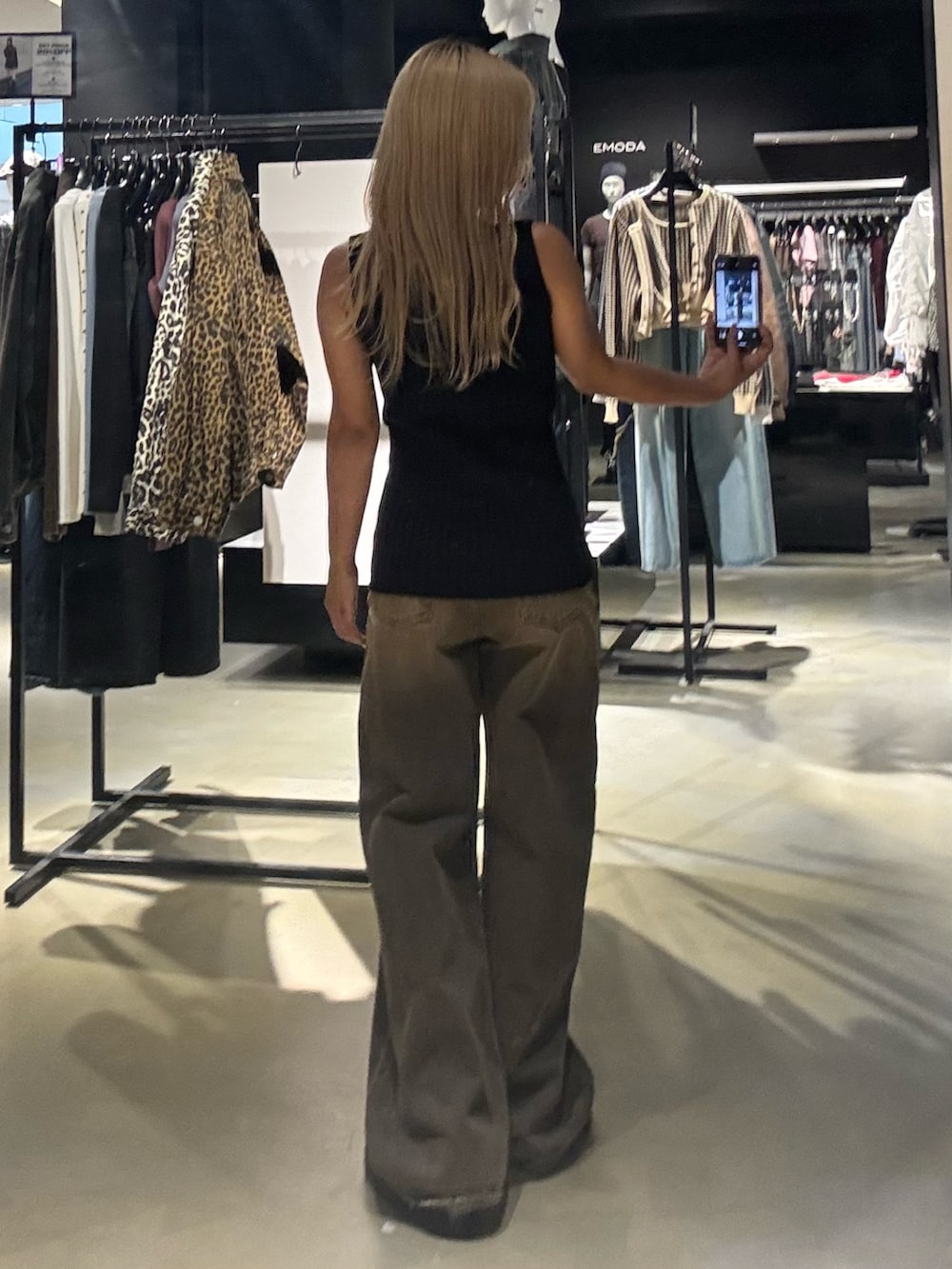 ブラック系のニット/セーター、ブラウン系のデニムパンツ、ブラック系のブーツを着用したレディースの秋コーディネートの3枚目の写真