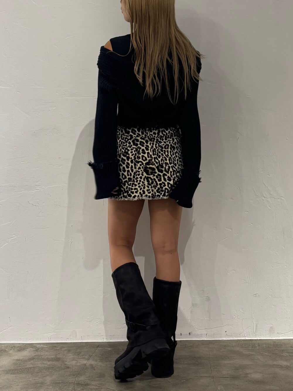 ホワイト系のスカート、ブラック系のニット/セーター、ブラック系のブーツを着用したレディースの秋コーディネートの3枚目の写真