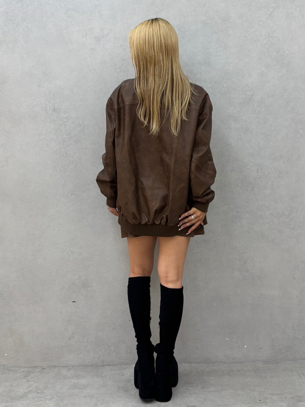 ブラック系のニット/セーター、ブラウン系のブルゾン、ブラック系のブーツを着用したレディースの秋コーディネートの3枚目の写真