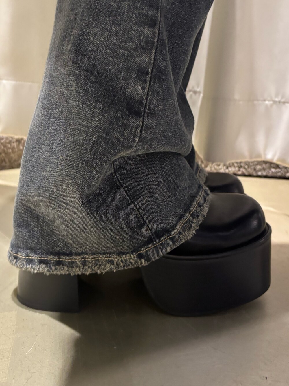 ブラック系のニット/セーター、ブルー系のデニムパンツ、ブラック系のブーツを着用したレディースの秋コーディネートの6枚目の写真