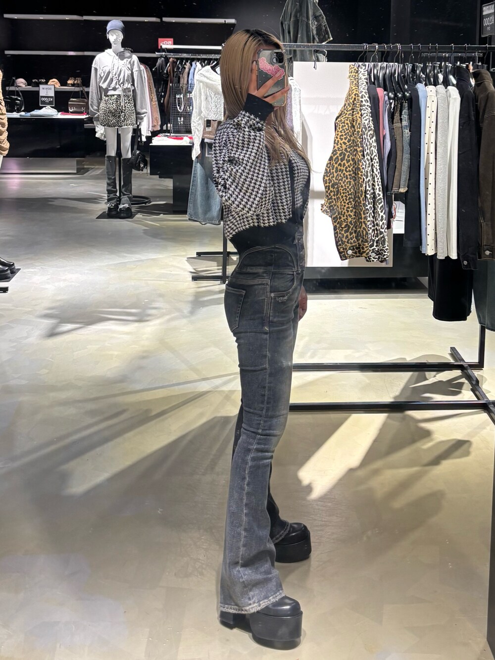 ブラック系のニット/セーター、ブルー系のデニムパンツ、ブラック系のブーツを着用したレディースの秋コーディネートの2枚目の写真