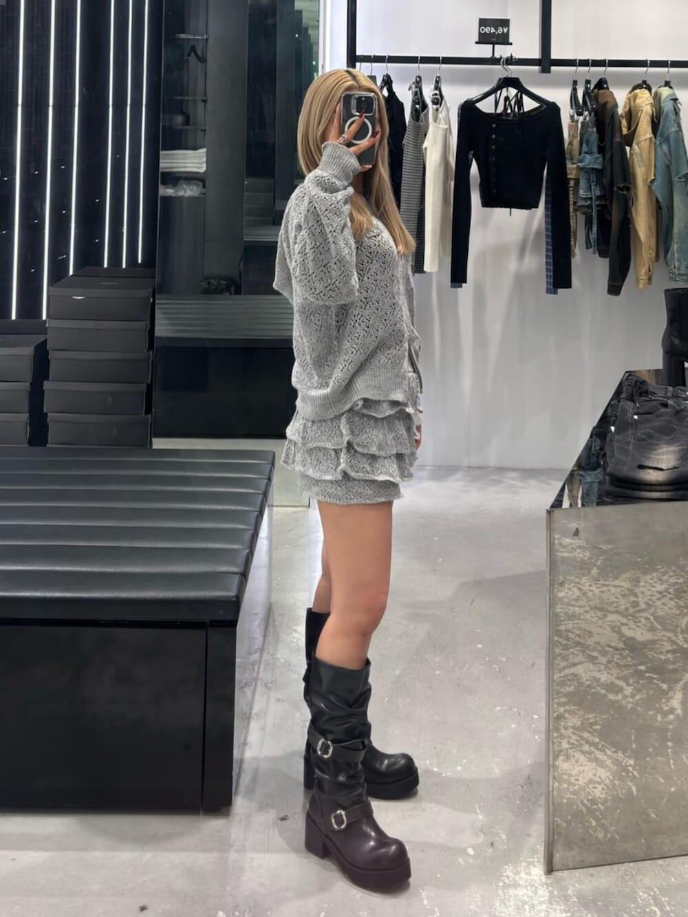 グレー系のパーカー、グレー系のスカート、ブラック系のブーツを着用したレディースの冬コーディネートの2枚目の写真