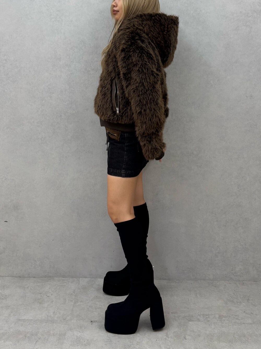 ブラウン系のブルゾン、ブラック系のスカート、ブラック系のブーツを着用したレディースの秋コーディネートの2枚目の写真