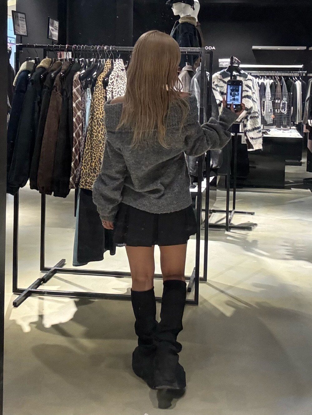 グレー系のニット/セーター、ブラック系のスカート、ブラック系のブーツを着用したレディースの秋コーディネートの3枚目の写真