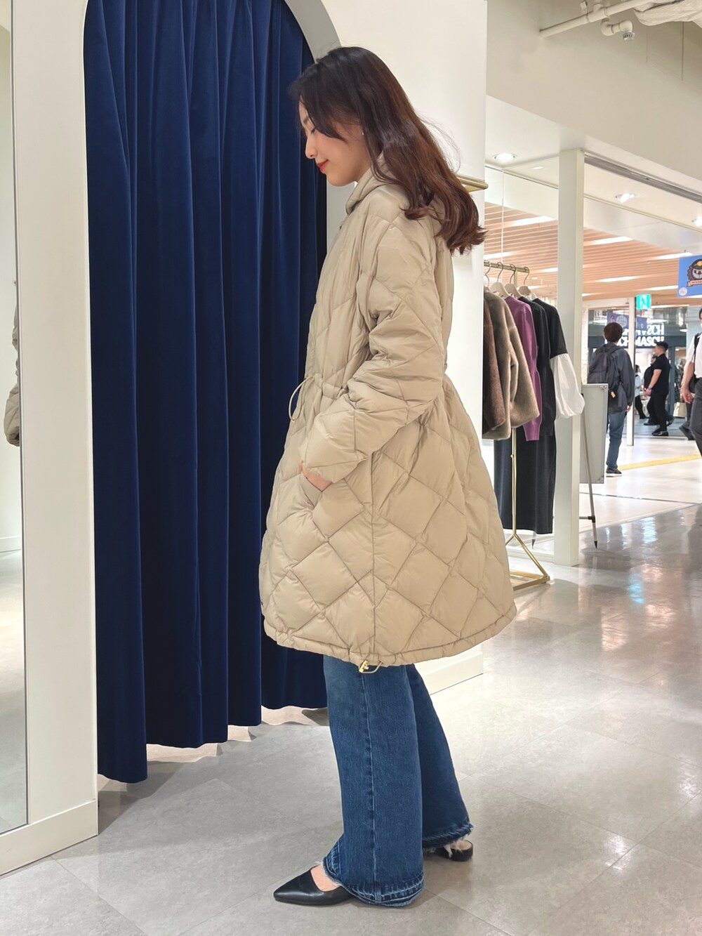 ブルー系のデニムパンツ、グレー系のニット/セーター、ベージュ系のダウンジャケット/コートを着用したレディースの秋コーディネートの2枚目の写真