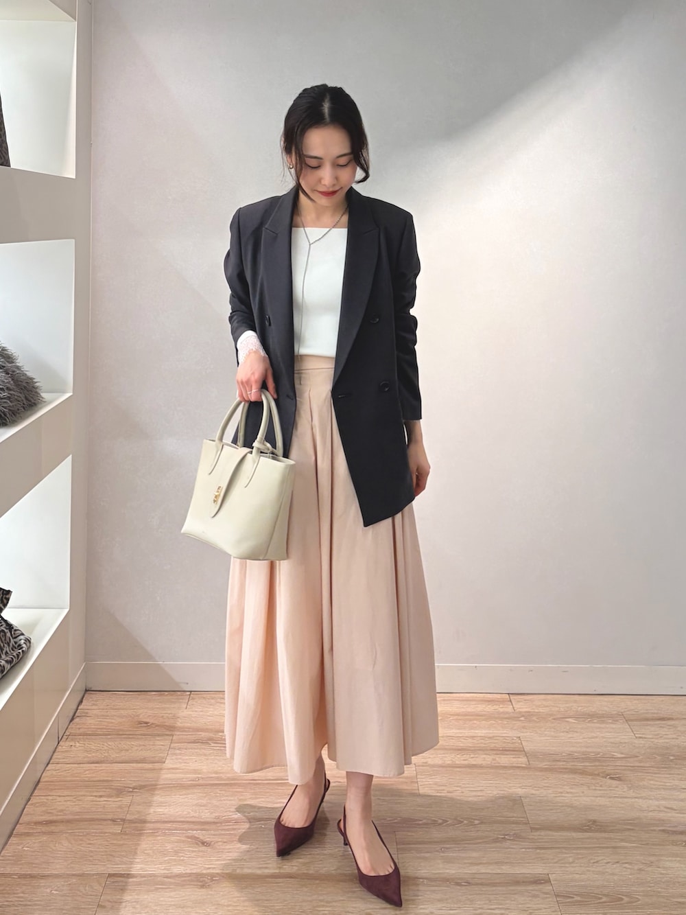 グレー系のテーラードジャケット、ホワイト系のニット/セーター、ベージュ系のトートバッグを着用したレディースの冬コーディネートの5枚目の写真