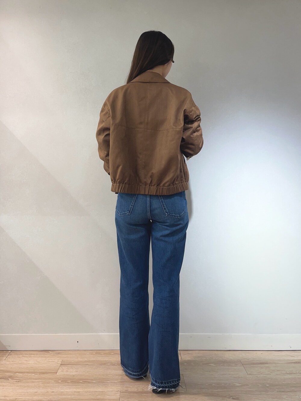 ブルー系のデニムパンツ、ホワイト系のニット/セーター、イエロー系のブルゾンを着用したレディースの秋コーディネートの4枚目の写真