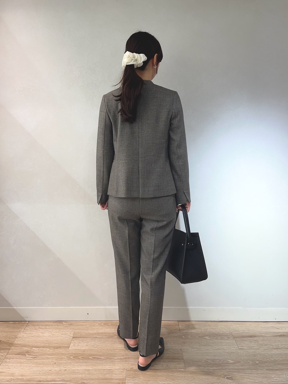 ベージュ系のノーカラージャケット、ホワイト系のニット/セーター、ブラック系のショルダーバッグを着用したレディースの秋コーディネートの3枚目の写真