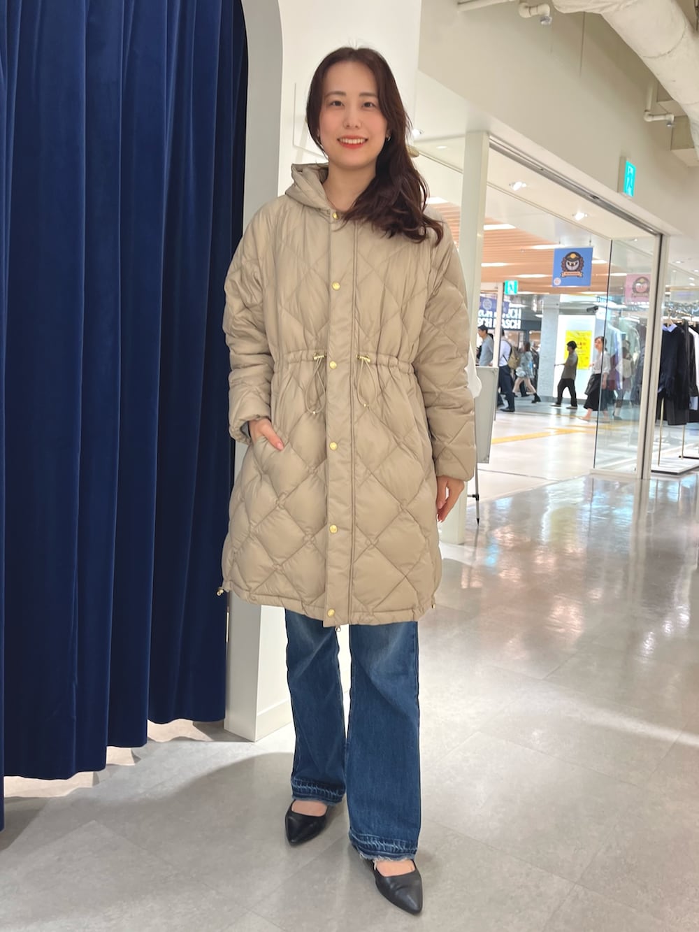 ブルー系のデニムパンツ、グレー系のニット/セーター、ベージュ系のダウンジャケット/コートを着用したレディースの秋コーディネートの5枚目の写真