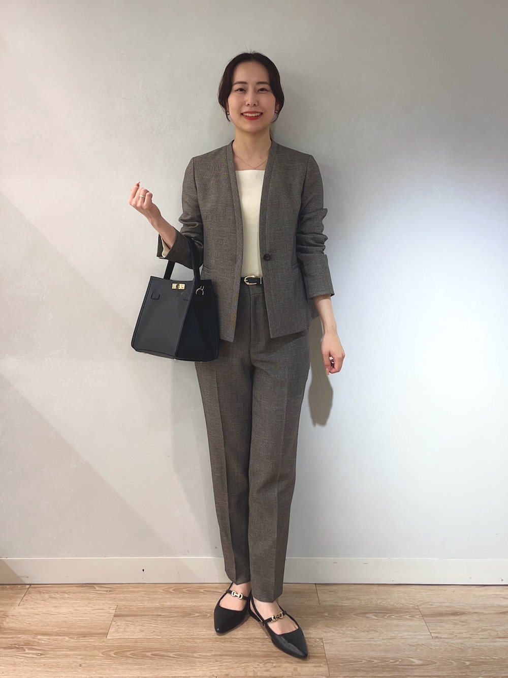 ベージュ系のノーカラージャケット、ホワイト系のニット/セーター、ブラック系のショルダーバッグを着用したレディースの秋コーディネートの5枚目の写真