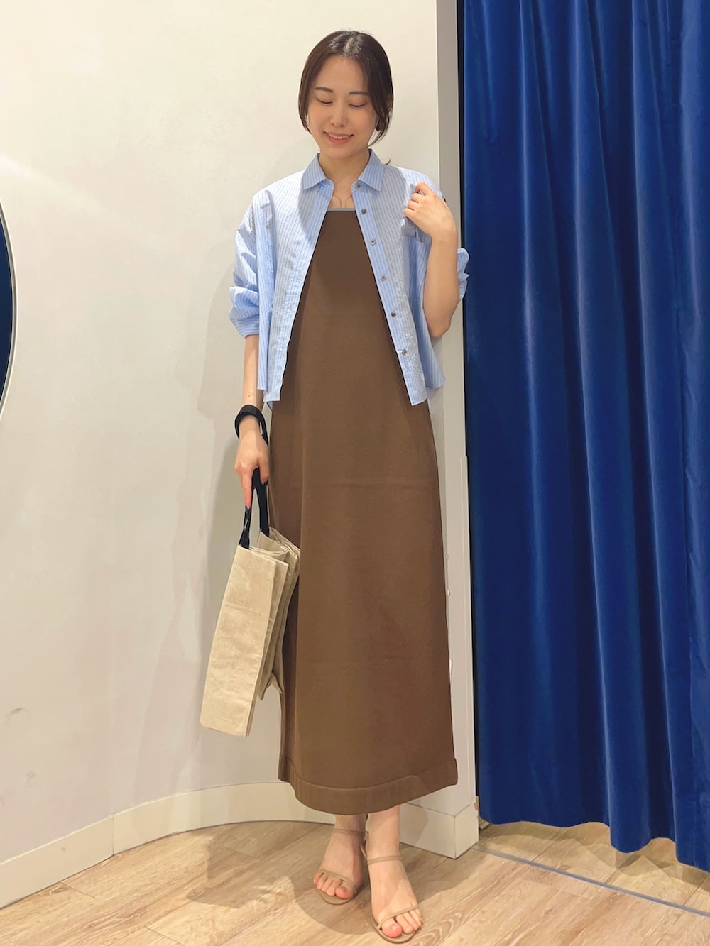 ブルー系のシャツ/ブラウス、ブラウン系のワンピース、ブラック系のバックパック/リュックを着用したレディースの夏コーディネートの5枚目の写真