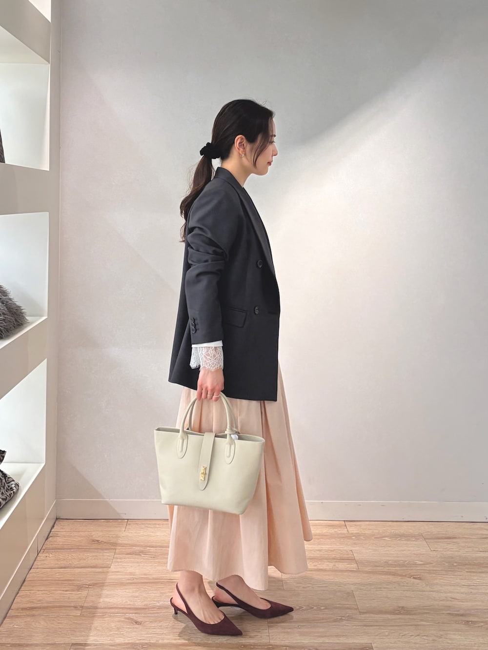 グレー系のテーラードジャケット、ホワイト系のニット/セーター、ベージュ系のトートバッグを着用したレディースの冬コーディネートの2枚目の写真