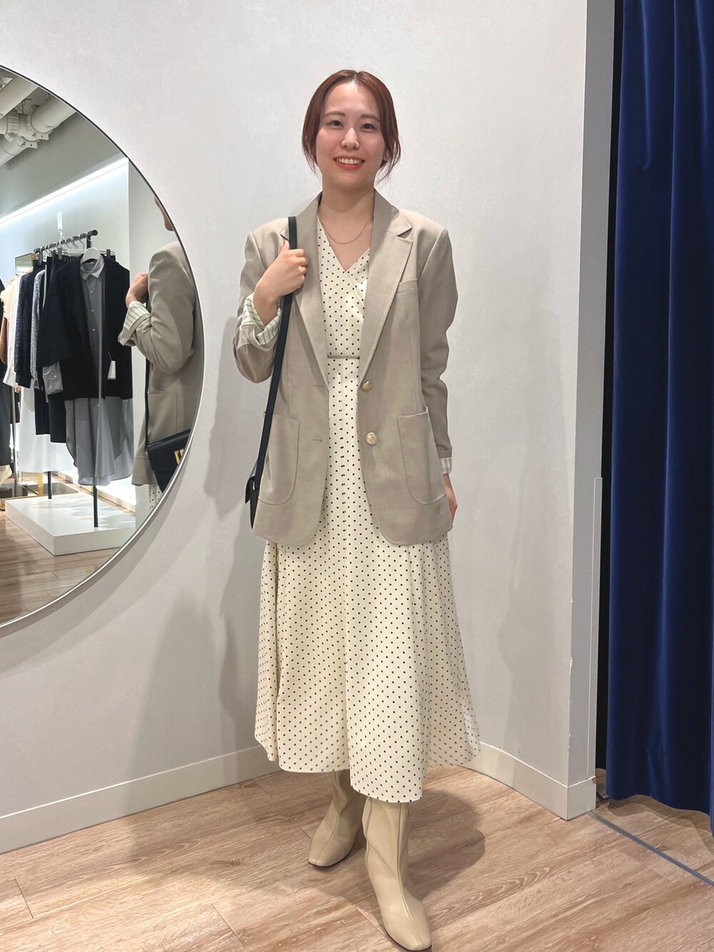 ベージュ系のテーラードジャケット、ホワイト系のワンピースを着用したレディースの秋コーディネートの2枚目の写真