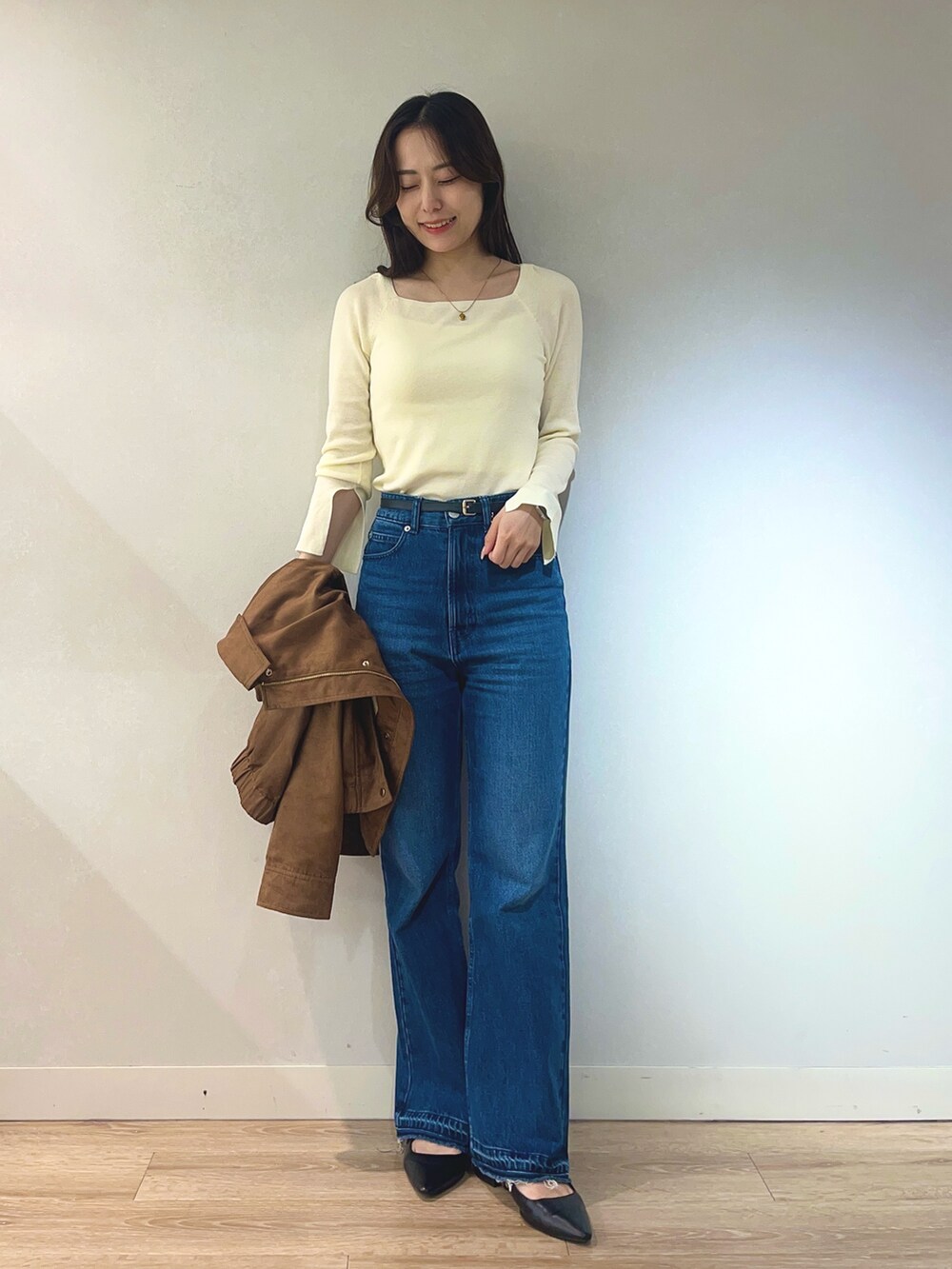 ブルー系のデニムパンツ、ホワイト系のニット/セーター、イエロー系のブルゾンを着用したレディースの秋コーディネートの2枚目の写真