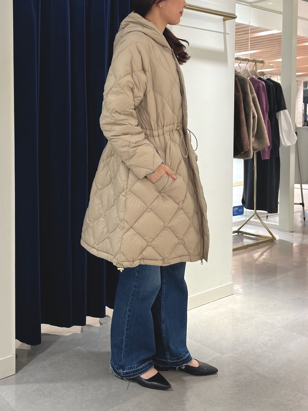 ブルー系のデニムパンツ、グレー系のニット/セーター、ベージュ系のダウンジャケット/コートを着用したレディースの秋コーディネートの4枚目の写真