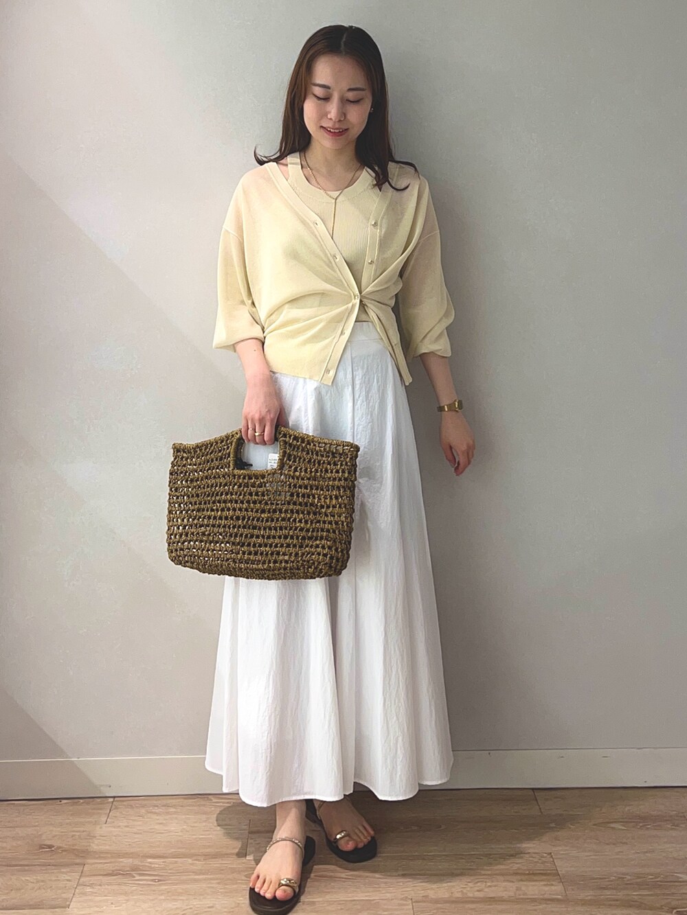ベージュ系のタンクトップ、ベージュ系のカーディガン/ボレロ、ベージュ系のかごバッグを着用したレディースの春コーディネートの2枚目の写真