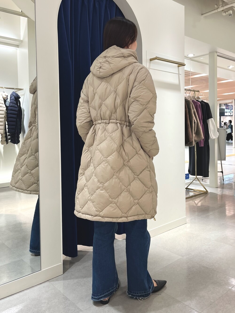 ブルー系のデニムパンツ、グレー系のニット/セーター、ベージュ系のダウンジャケット/コートを着用したレディースの秋コーディネートの3枚目の写真