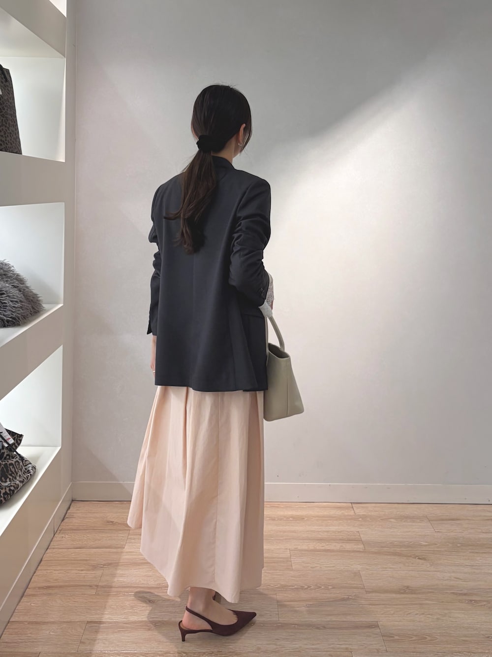 グレー系のテーラードジャケット、ホワイト系のニット/セーター、ベージュ系のトートバッグを着用したレディースの冬コーディネートの3枚目の写真