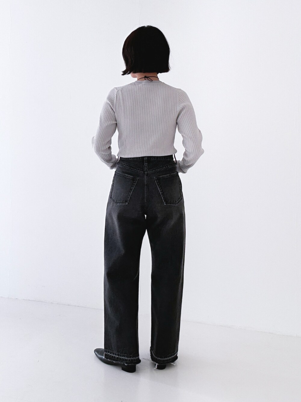 ブラック系のデニムパンツ、ブラック系のブーツ、グレー系のニット/セーターを着用したレディースの冬コーディネートの2枚目の写真