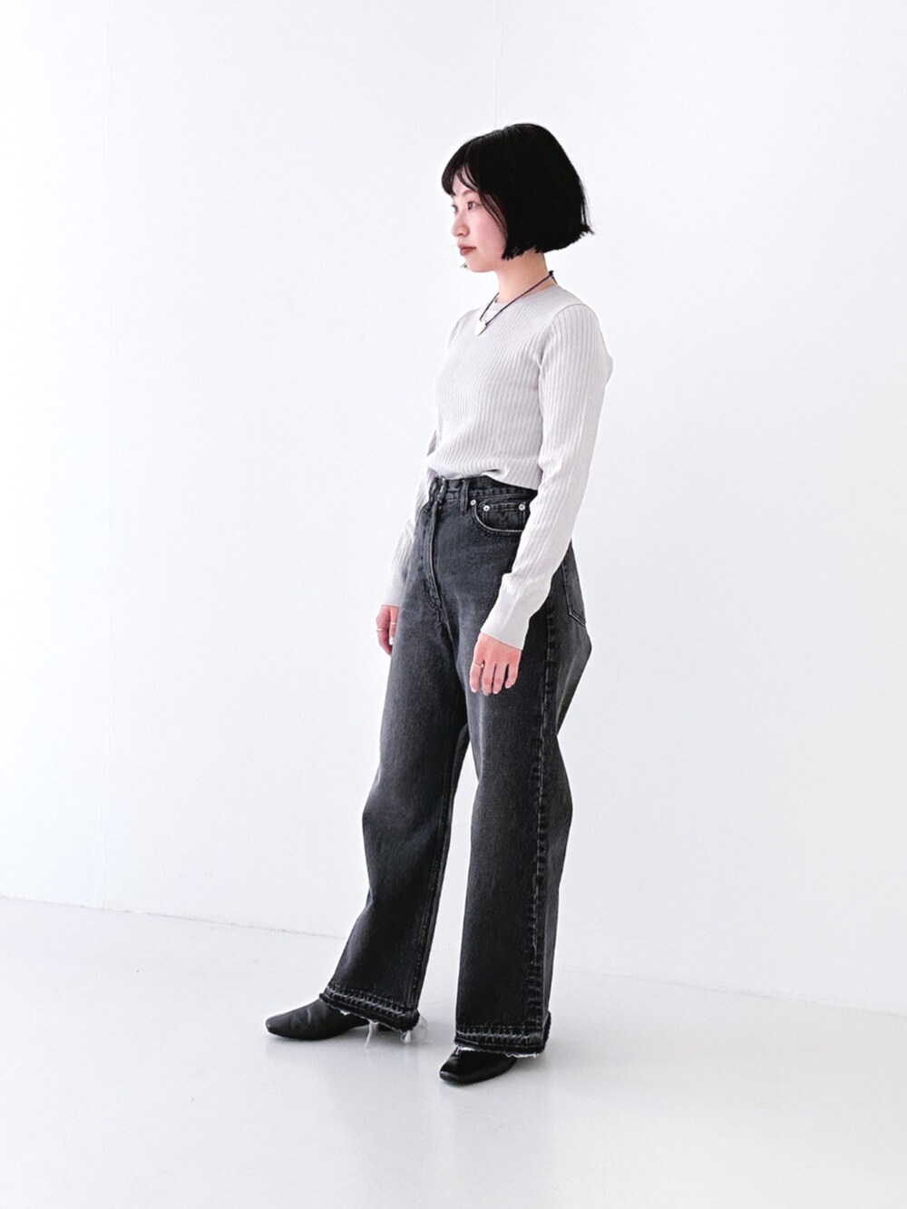 ブラック系のデニムパンツ、ブラック系のブーツ、グレー系のニット/セーターを着用したレディースの冬コーディネートの4枚目の写真