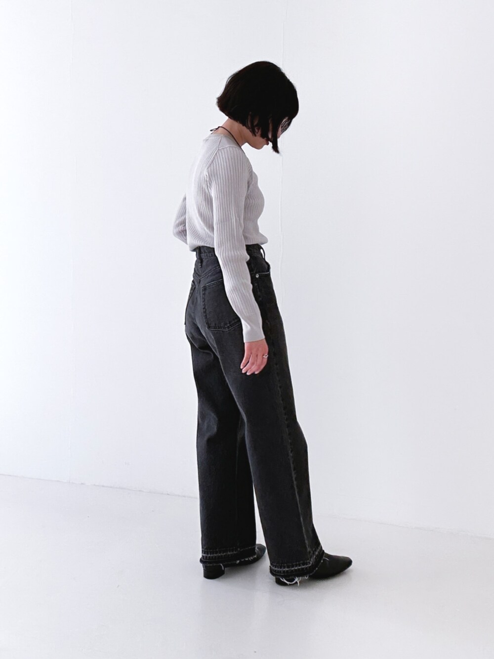 ブラック系のデニムパンツ、ブラック系のブーツ、グレー系のニット/セーターを着用したレディースの冬コーディネートの3枚目の写真