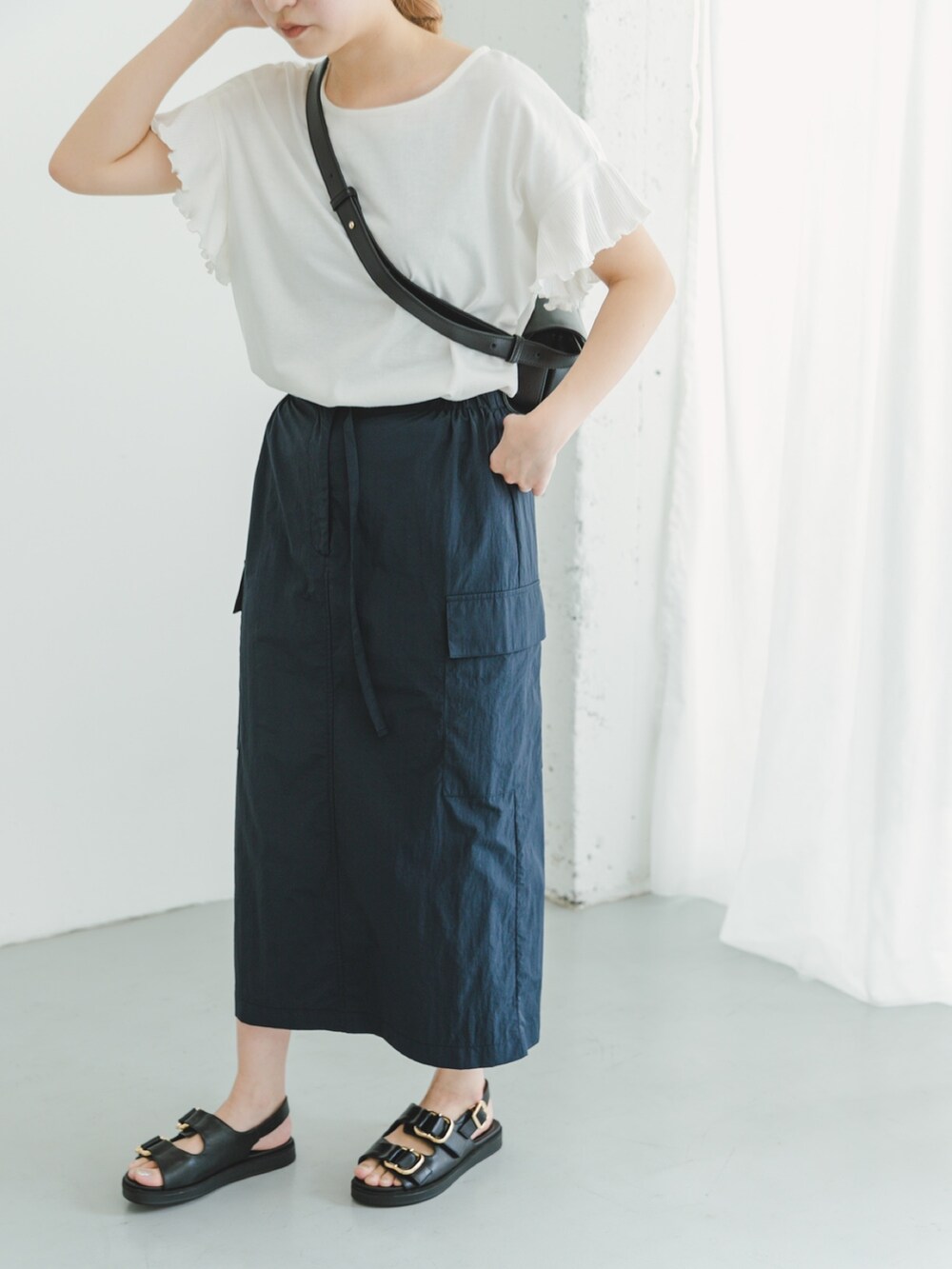 ブルー系のスカート、ホワイト系のTシャツ/カットソー、ブラック系のショルダーバッグを着用したレディースの夏コーディネートの2枚目の写真