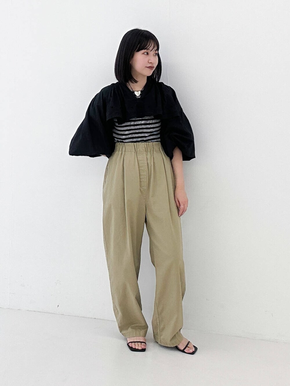 ベージュ系のその他パンツ、ブラック系のサンダル、ブラック系のTシャツ/カットソーを着用したレディースの夏コーディネートの2枚目の写真