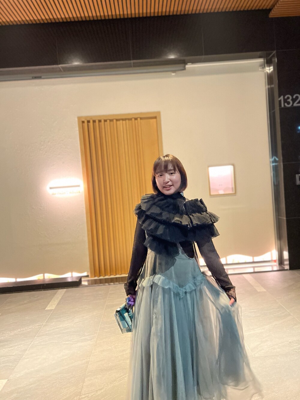 ブルー系のジャンパースカート、ブラック系のカーディガン/ボレロ、ブラック系のサンダルを着用したレディースの春コーディネートの2枚目の写真