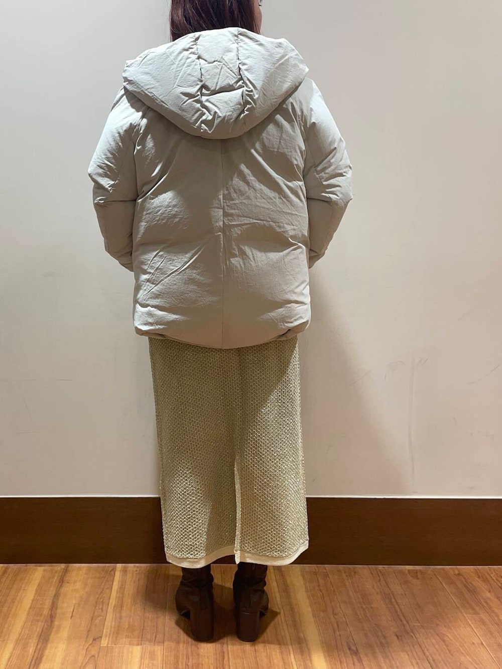 ホワイト系のダウンジャケット/コート、ゴールド系のスカート、ブルー系のニット/セーターを着用したレディースの冬コーディネートの3枚目の写真