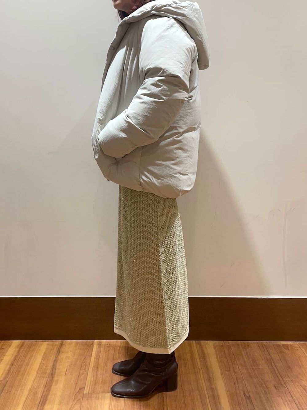 ホワイト系のダウンジャケット/コート、ゴールド系のスカート、ブルー系のニット/セーターを着用したレディースの冬コーディネートの2枚目の写真