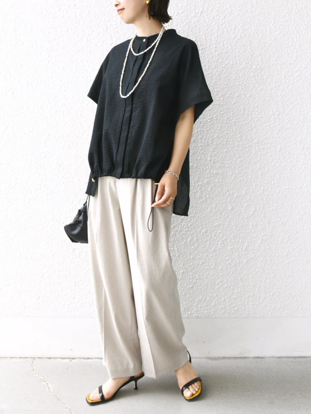 ベージュ系のその他パンツ、ブラック系のシャツ/ブラウス、ホワイト系のネックレスを着用したレディースの夏コーディネートの2枚目の写真