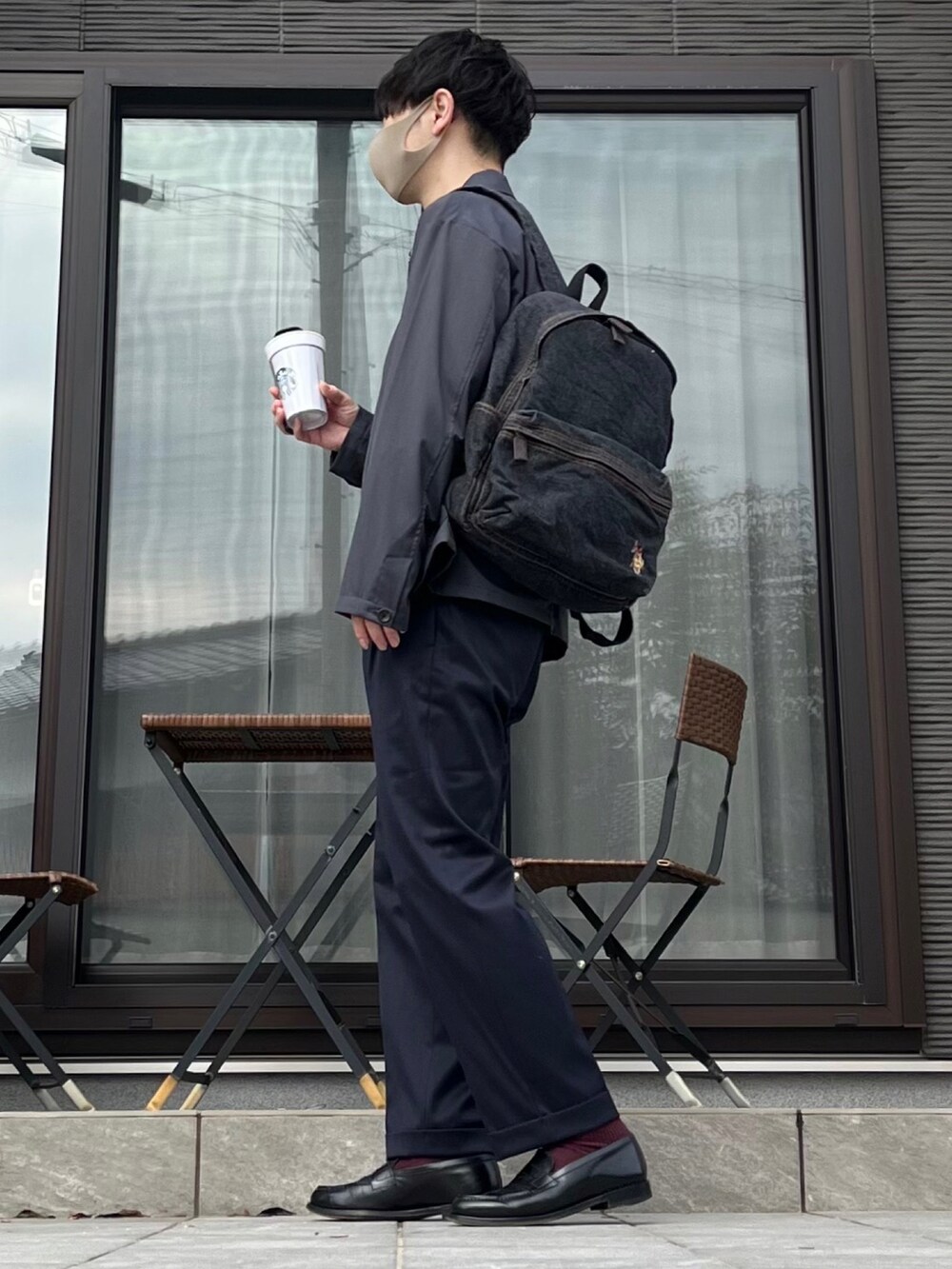 ブラック系のバックパック/リュック、グレー系のカバーオール、グレー系のTシャツ/カットソーを着用したメンズの春コーディネートの2枚目の写真