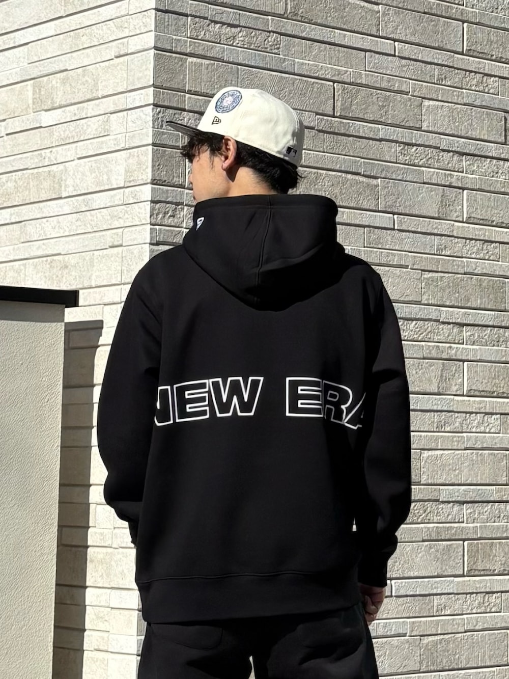 ブラック系のパーカー、ブラック系のスニーカー、ホワイト系のキャップを着用したメンズの冬コーディネートの4枚目の写真