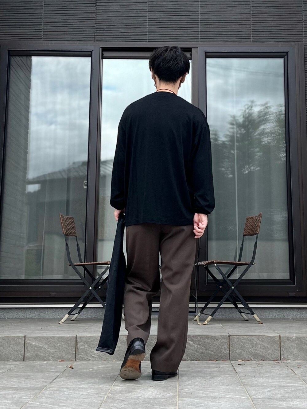 ブラウン系のスラックス、ブラック系のTシャツ/カットソー、ブラック系のローファーを着用したメンズの秋コーディネートの2枚目の写真