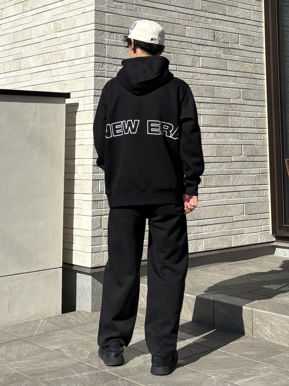 ブラック系のパーカー、ブラック系のスニーカー、ホワイト系のキャップを着用したメンズの冬コーディネートの2枚目の写真