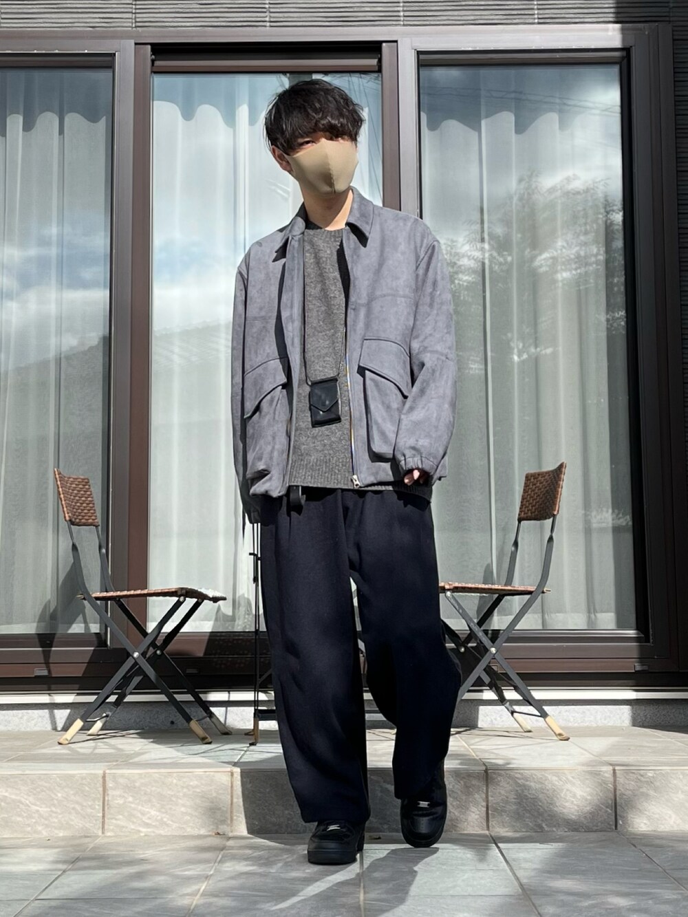 グレー系のブルゾン、グレー系のニット/セーター、ブルー系のスラックスを着用したメンズの秋コーディネートの2枚目の写真