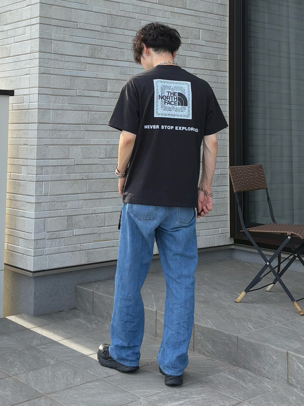 ブラック系のTシャツ/カットソー、ブラック系のサンダル、シルバー系のブレスレットを着用したメンズの夏コーディネートの2枚目の写真