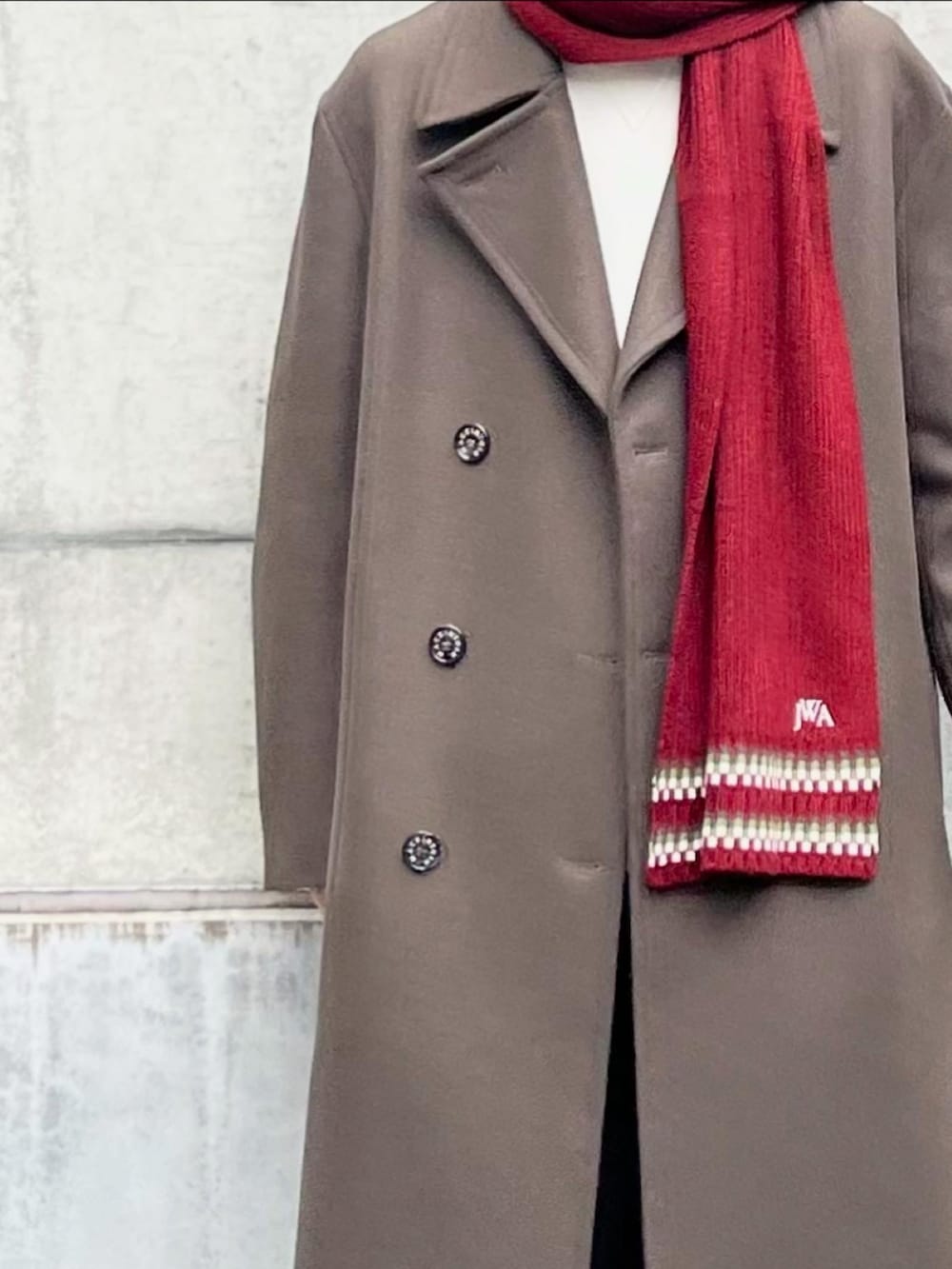 グリーン系のトレンチコート、ホワイト系のトップス、ブラック系のスウェットパンツを着用したメンズの冬コーディネートの5枚目の写真