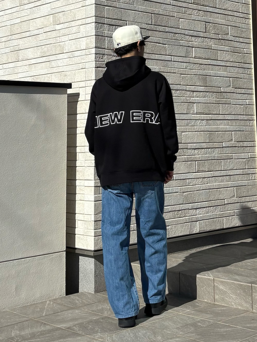 ブラック系のパーカー、ホワイト系のキャップを着用したメンズの秋コーディネートの2枚目の写真