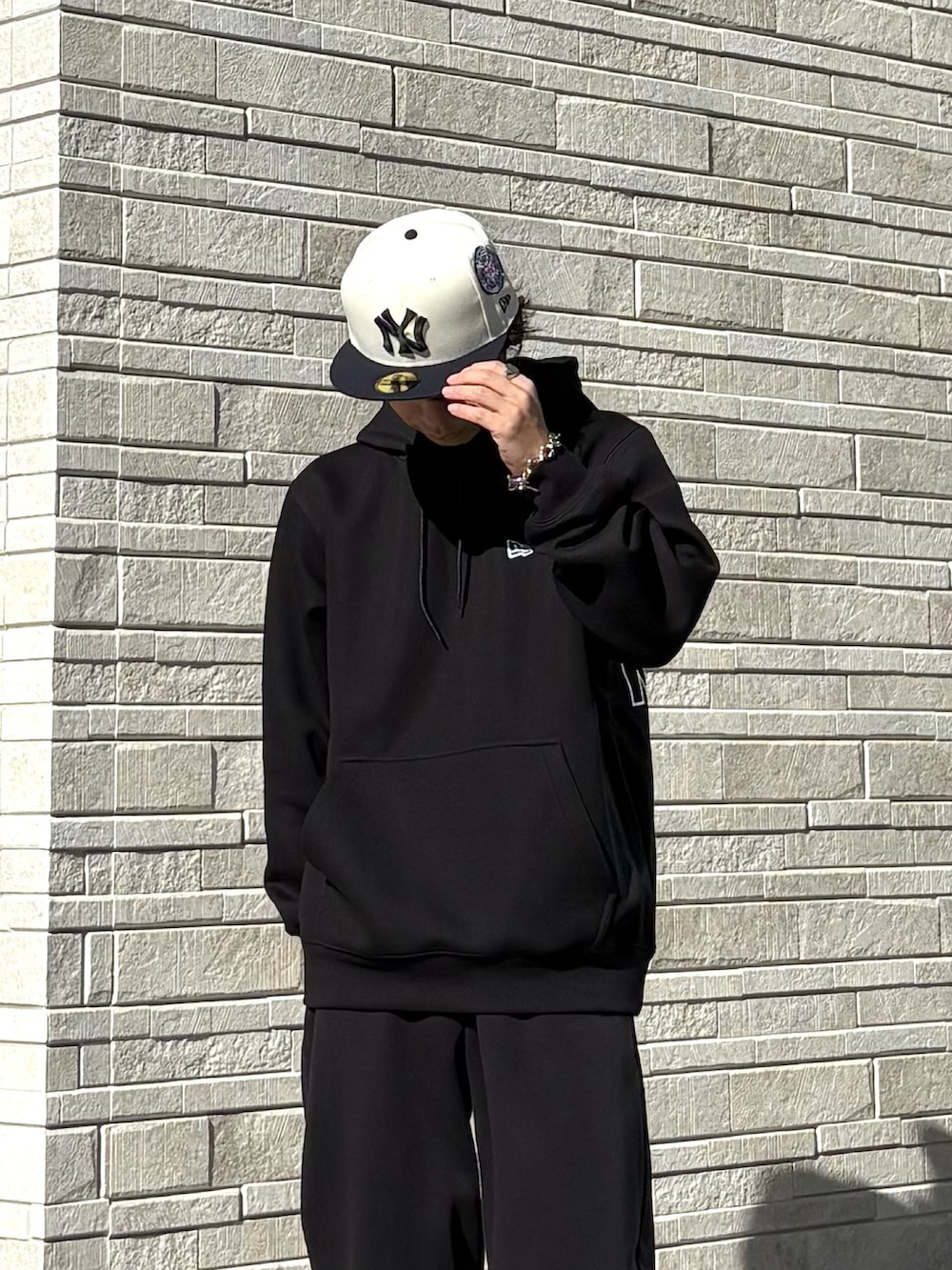 ブラック系のパーカー、ブラック系のスニーカー、ホワイト系のキャップを着用したメンズの冬コーディネートの3枚目の写真