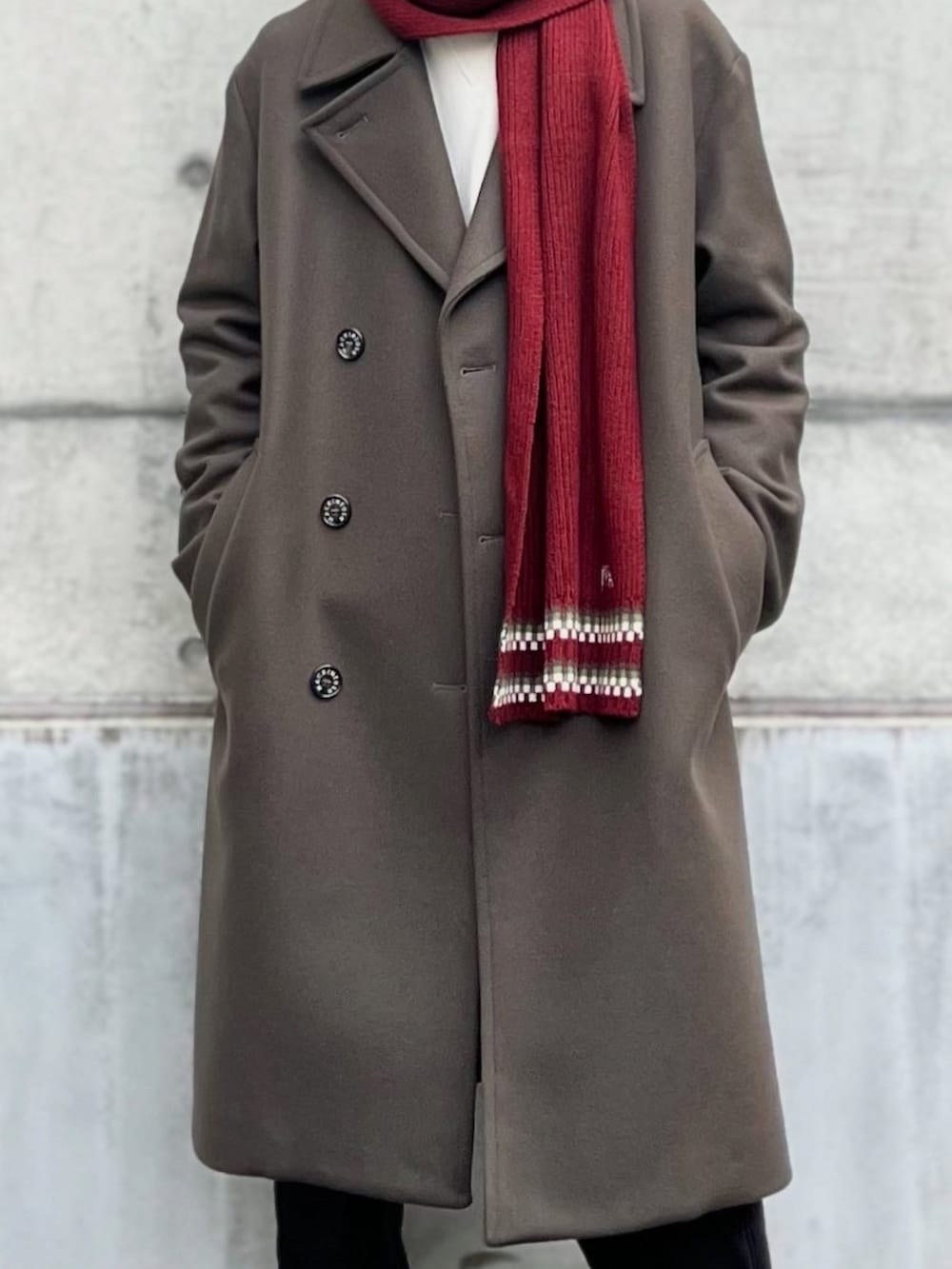 グリーン系のトレンチコート、ホワイト系のトップス、ブラック系のスウェットパンツを着用したメンズの冬コーディネートの2枚目の写真