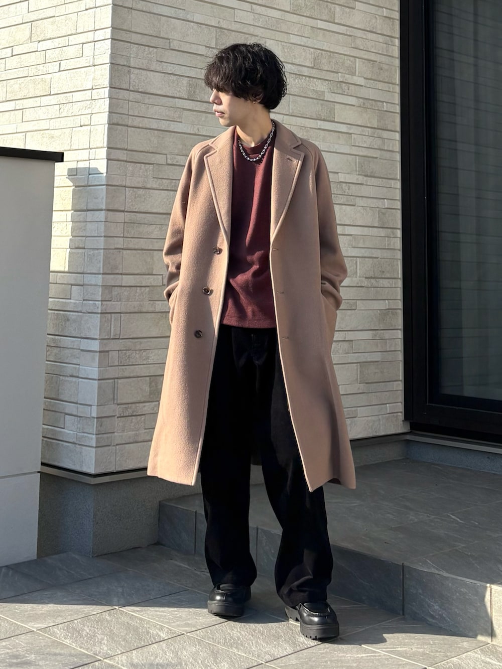 ブラウン系のTシャツ/カットソー、ベージュ系のチェスターコート、ブラック系のその他パンツを着用したメンズの冬コーディネートの2枚目の写真
