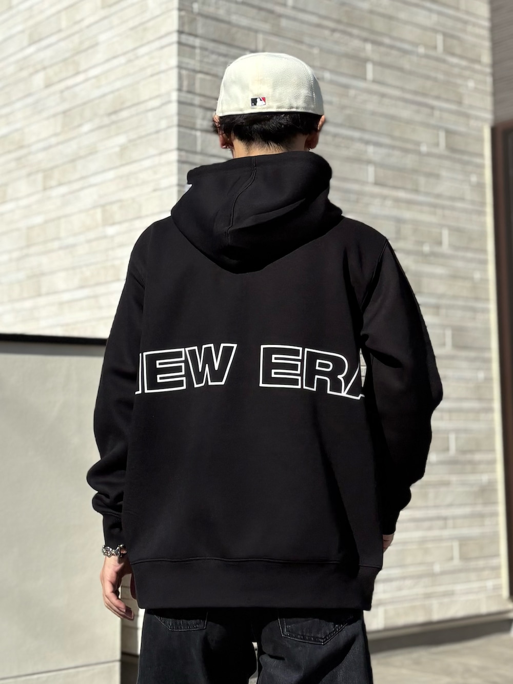 ブラック系のパーカー、ホワイト系のキャップ、グレー系のベルトを着用したメンズの冬コーディネートの4枚目の写真