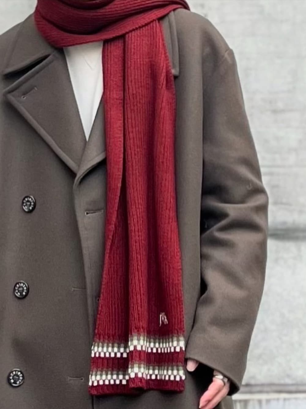 グリーン系のトレンチコート、ホワイト系のトップス、ブラック系のスウェットパンツを着用したメンズの冬コーディネートの3枚目の写真