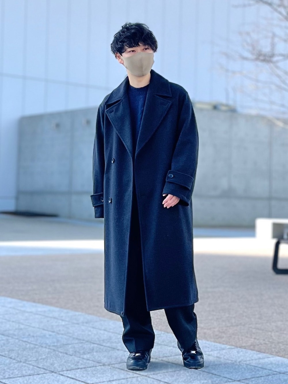 ブルー系のニット/セーター、グレー系のその他アウター、グレー系のスラックスを着用したメンズの冬コーディネートの2枚目の写真