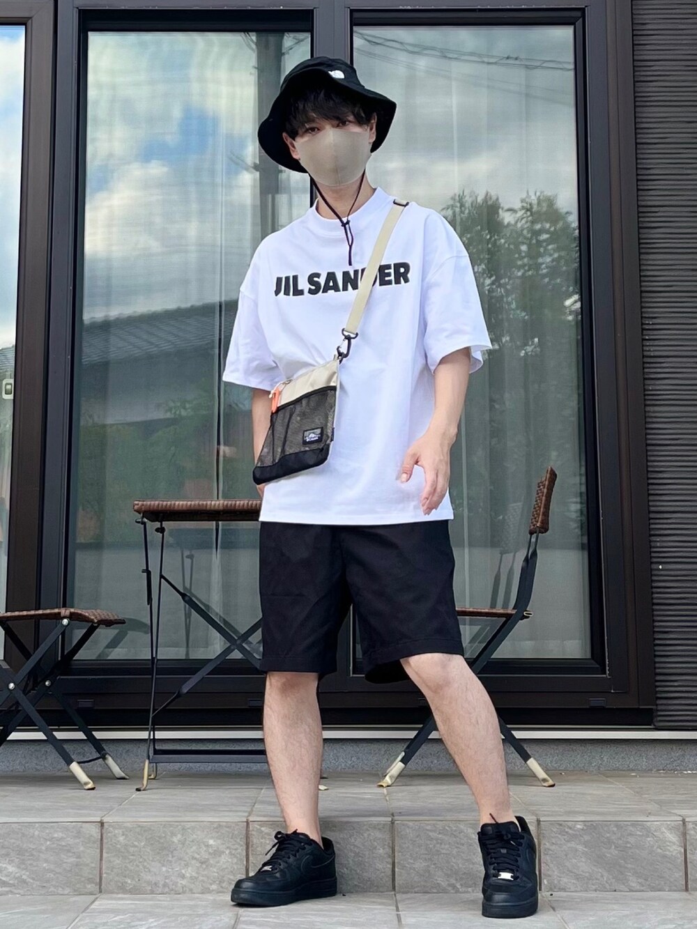 ベージュ系のショルダーバッグ、ホワイト系のTシャツ/カットソー、ブラック系のパンツを着用したメンズの夏コーディネートの2枚目の写真