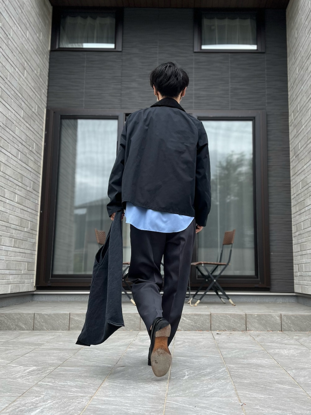 ブラック系のブルゾン、ブルー系のシャツ/ブラウス、グレー系のスラックスを着用したメンズの秋コーディネートの2枚目の写真